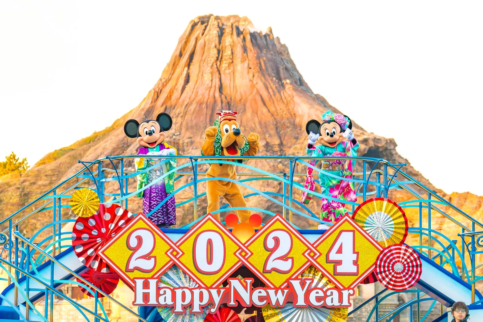 ミッキー、プルート、ミニーが火山を背景に「2024 Happy New Year」の看板とともに登場。