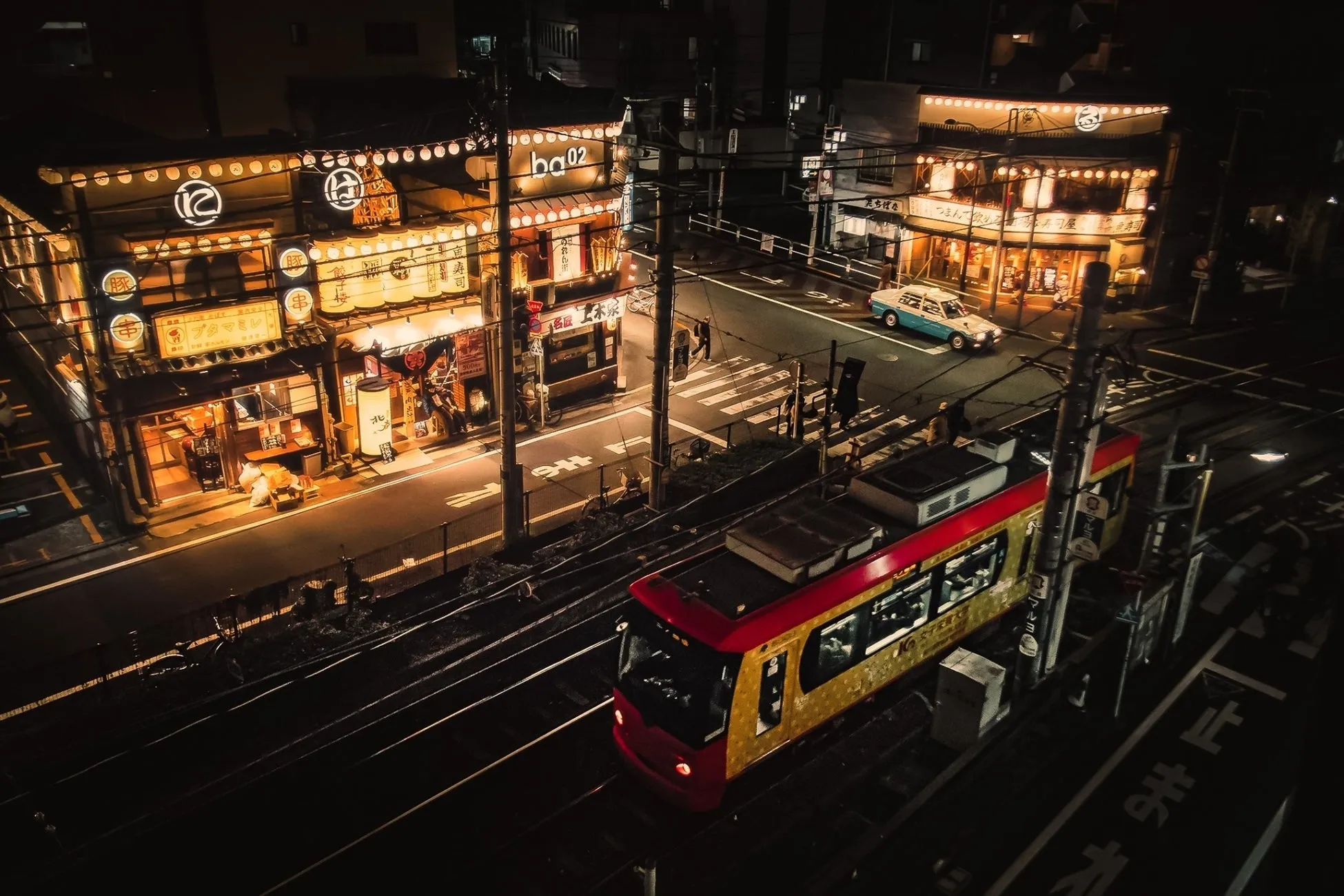 夜の大塚のれん街と走行する赤い電車