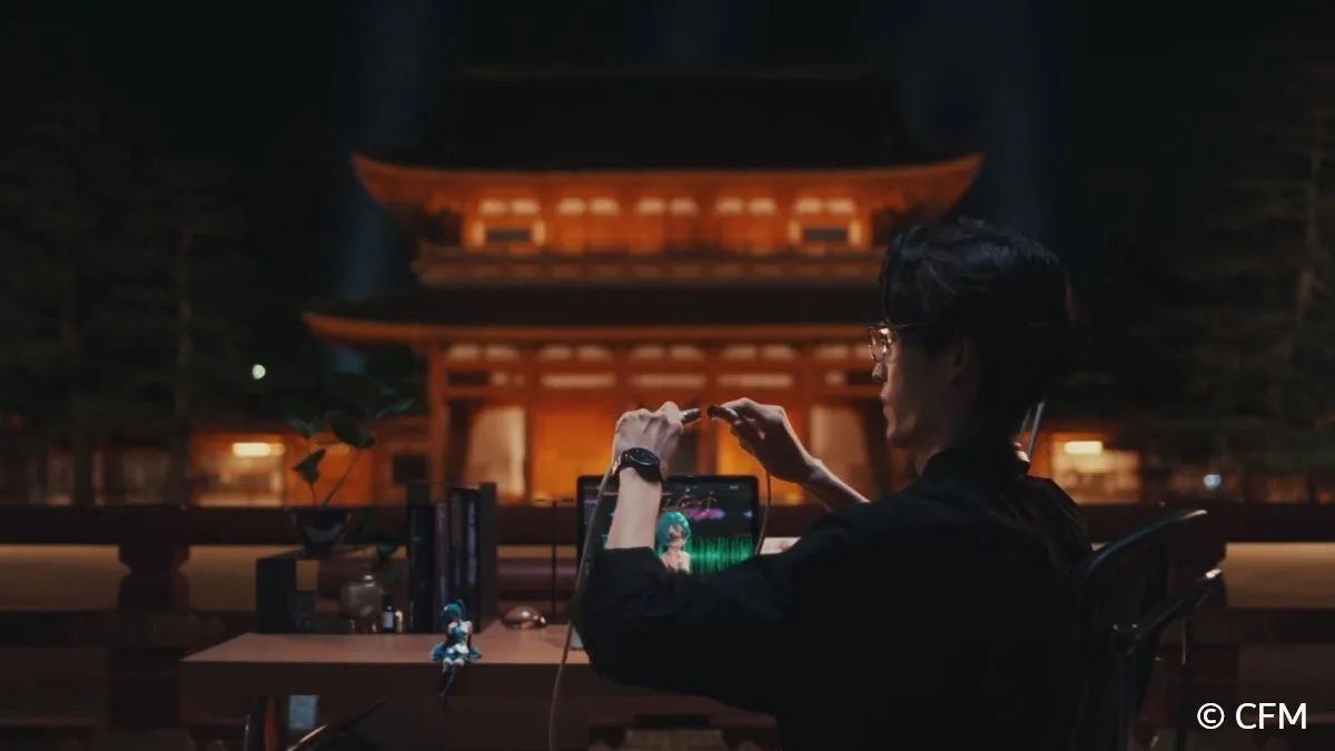 初音ミクの映像が流れるパソコンと夜の伝統的な建物