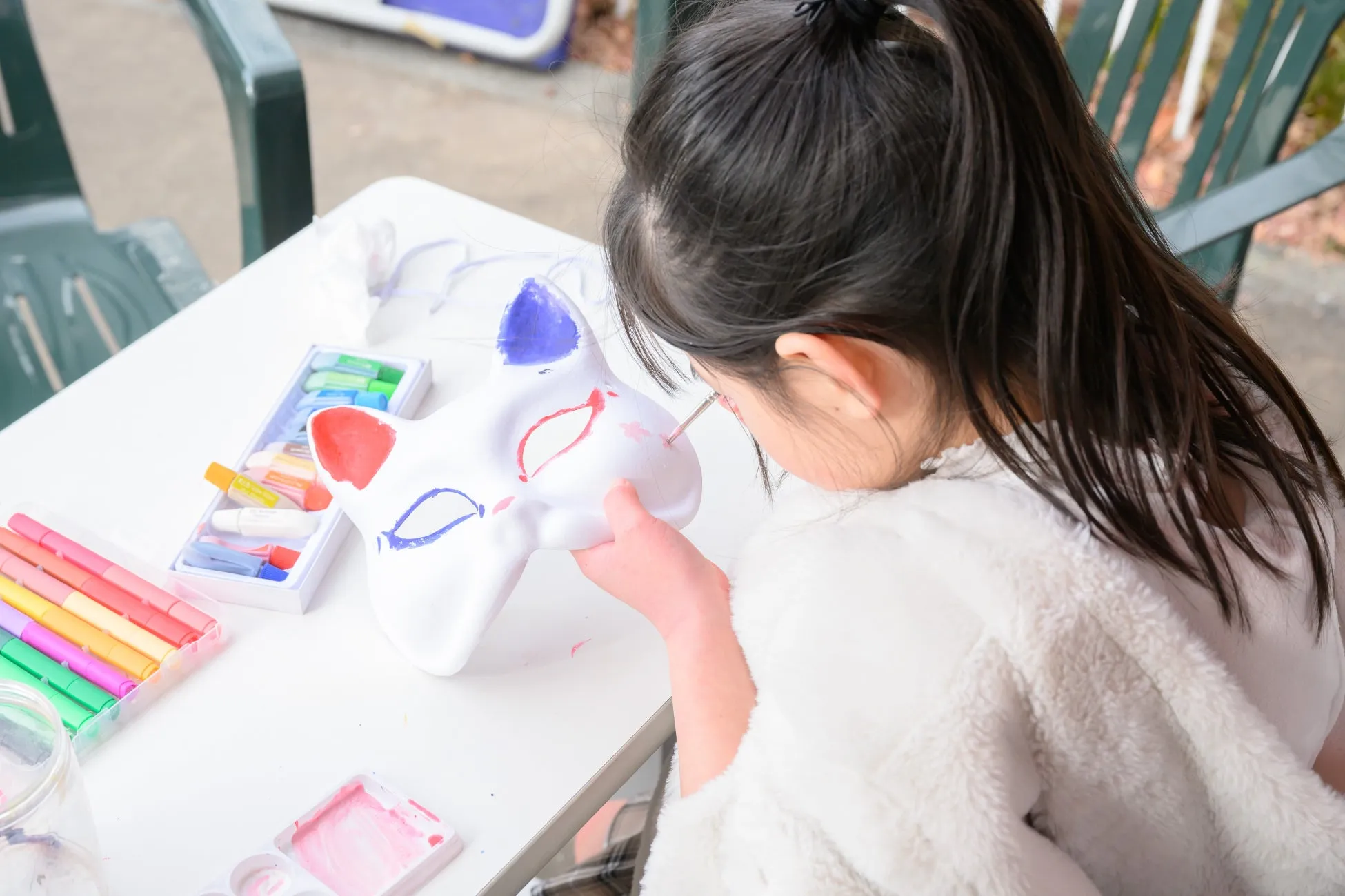 子供が狐の面に赤と青を塗る