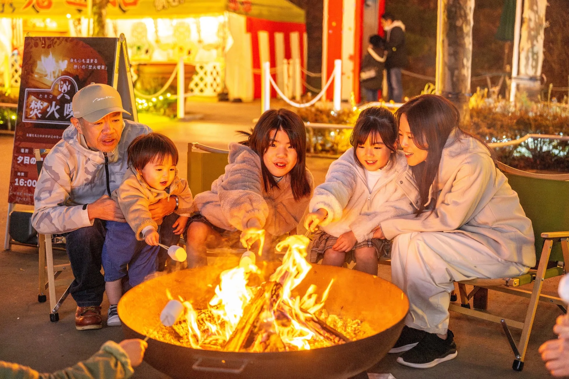 焚火でマシュマロを焼く家族