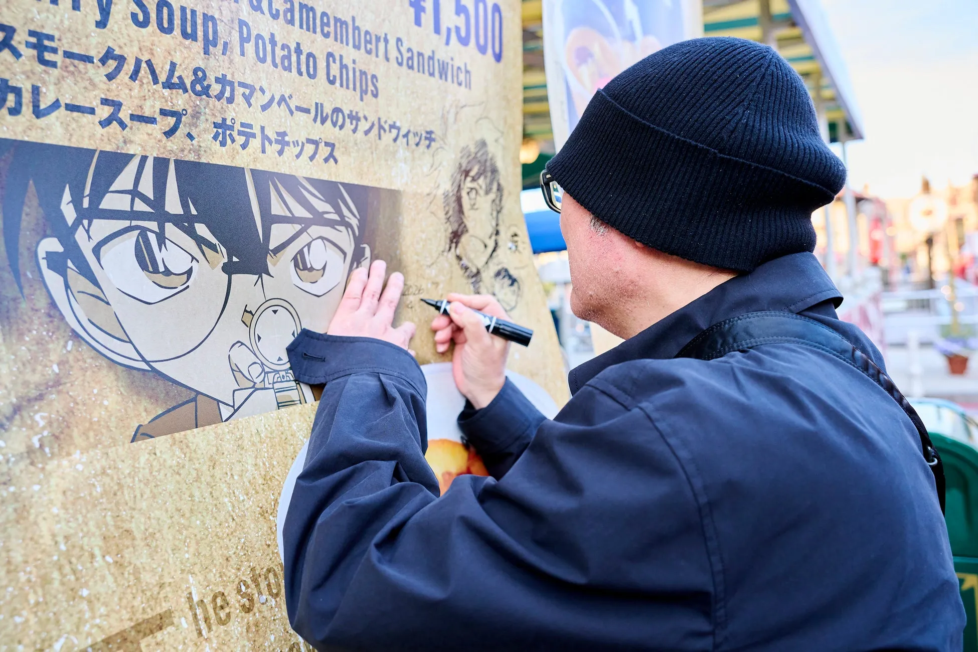 『名探偵コナン』のポスターにサインをする人物