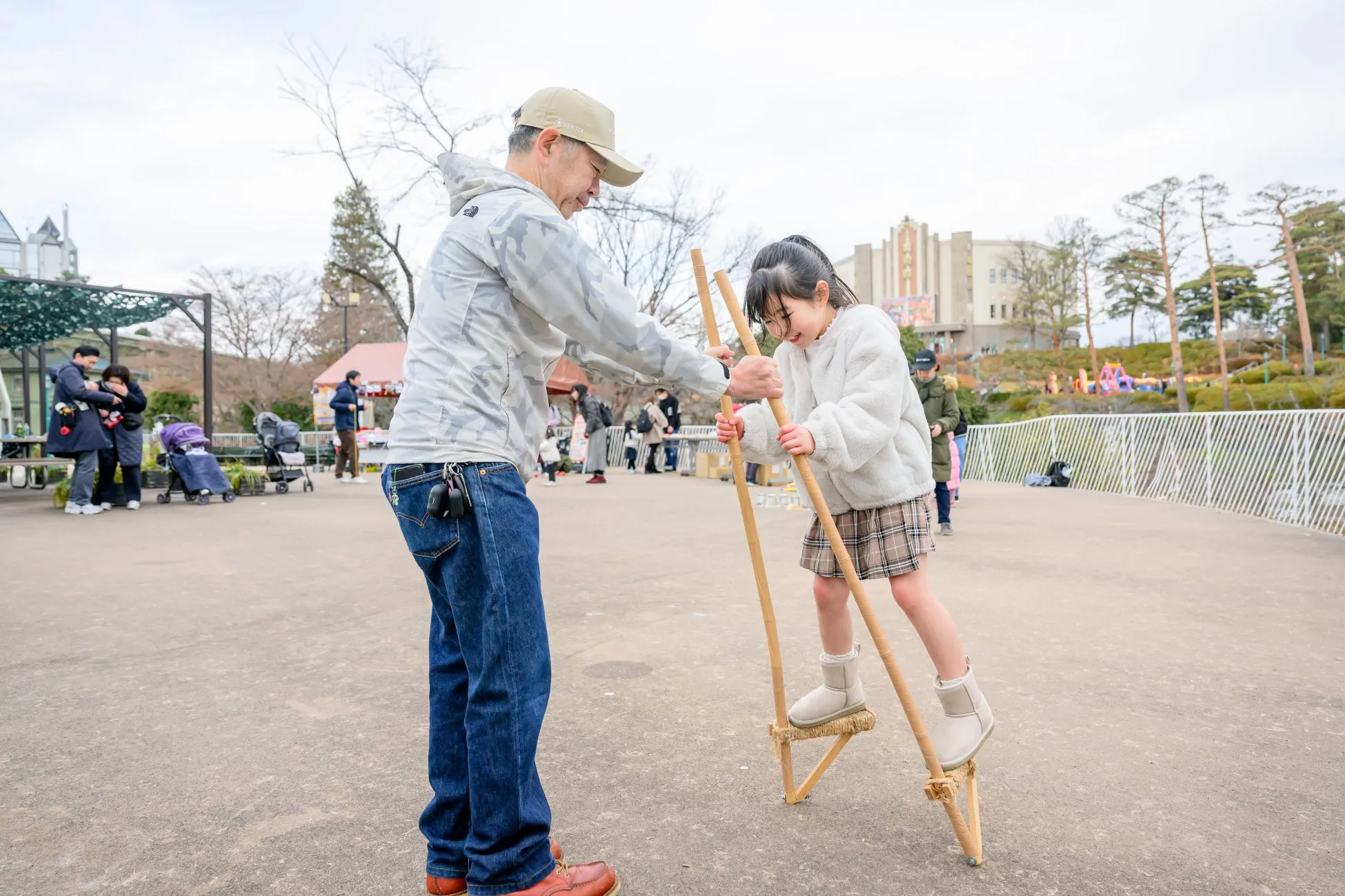 西武園ゆうえんちで竹馬に挑戦する子供とサポートする大人