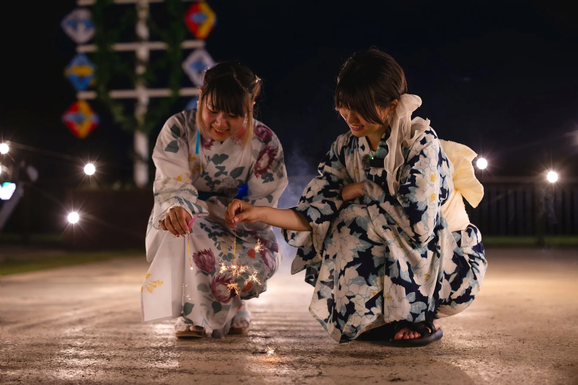 浴衣を着た女性が手持ち花火を楽しむ