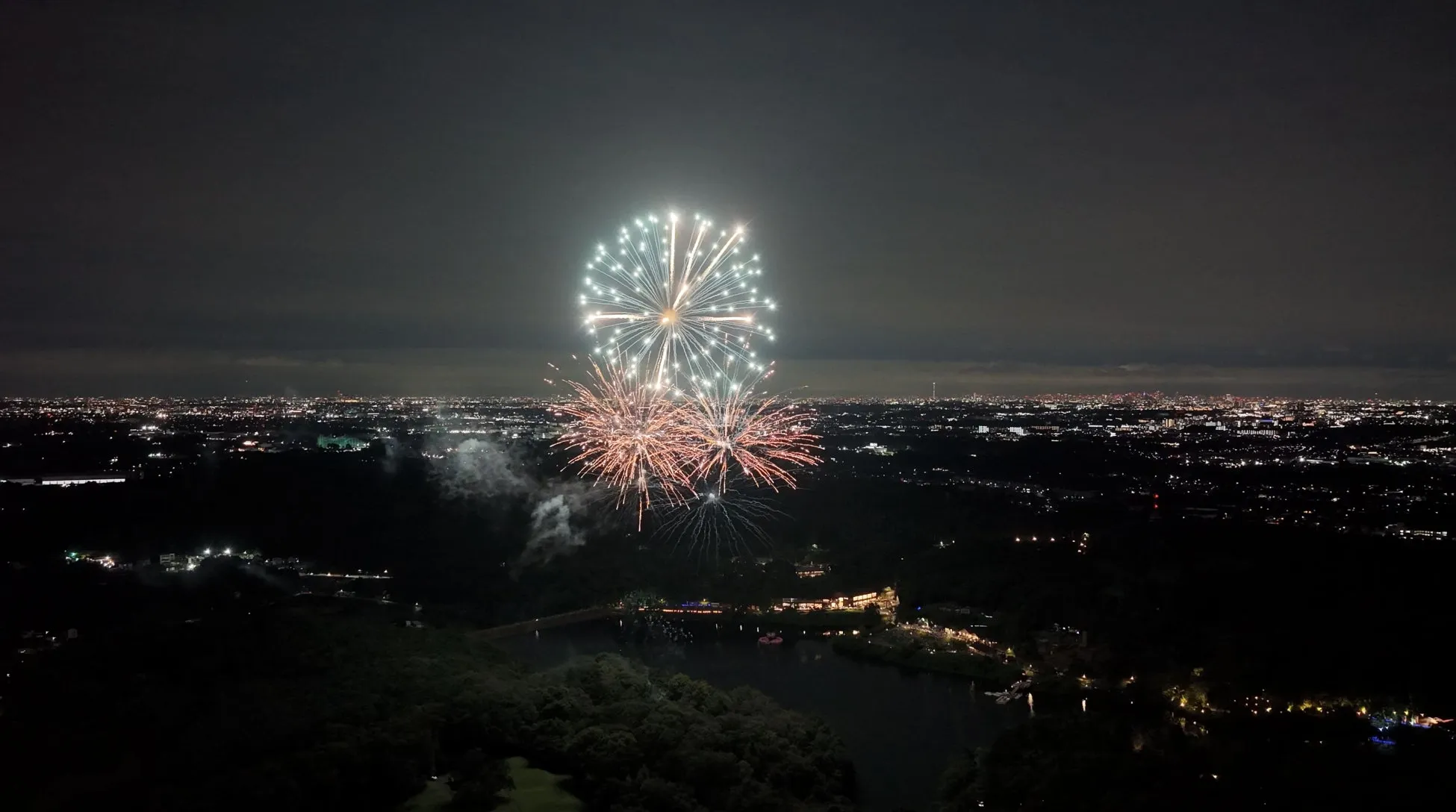 夜空に広がる打ち上げ花火と街の明かり