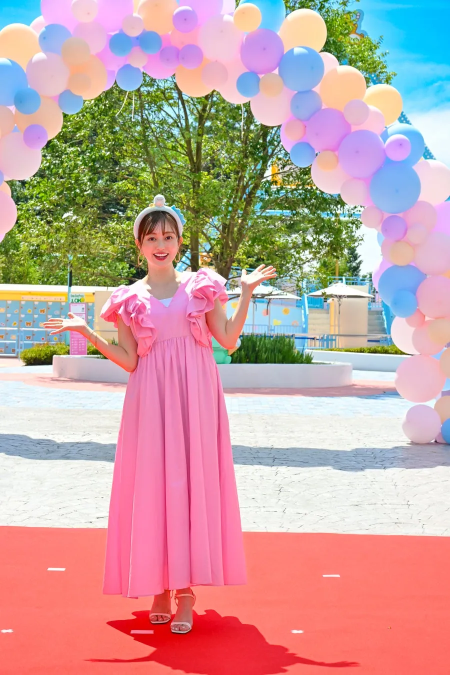 ピンクのドレスを着た女性がバルーンアーチの前に立つ
