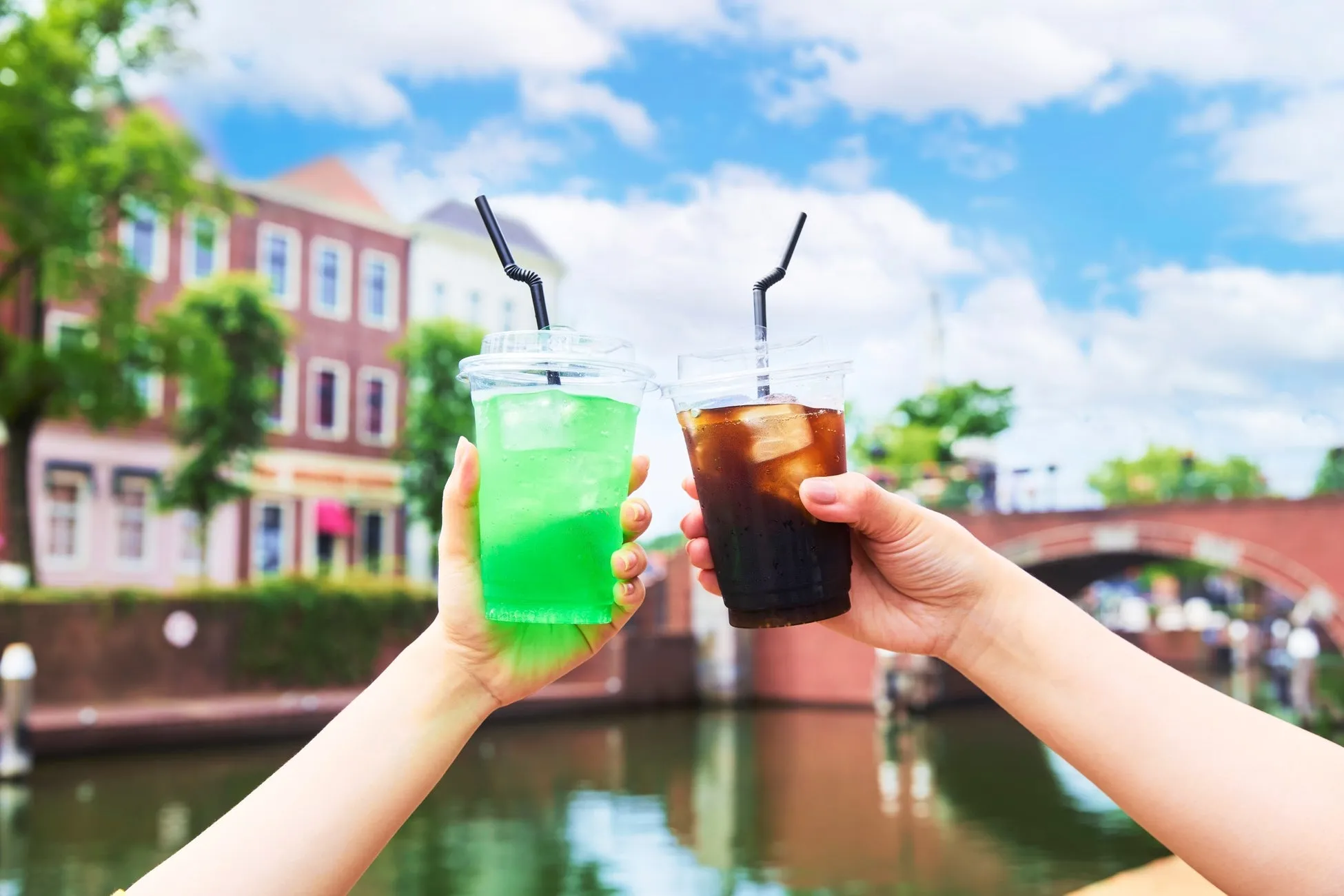 緑色のソーダとコーラを持つ手