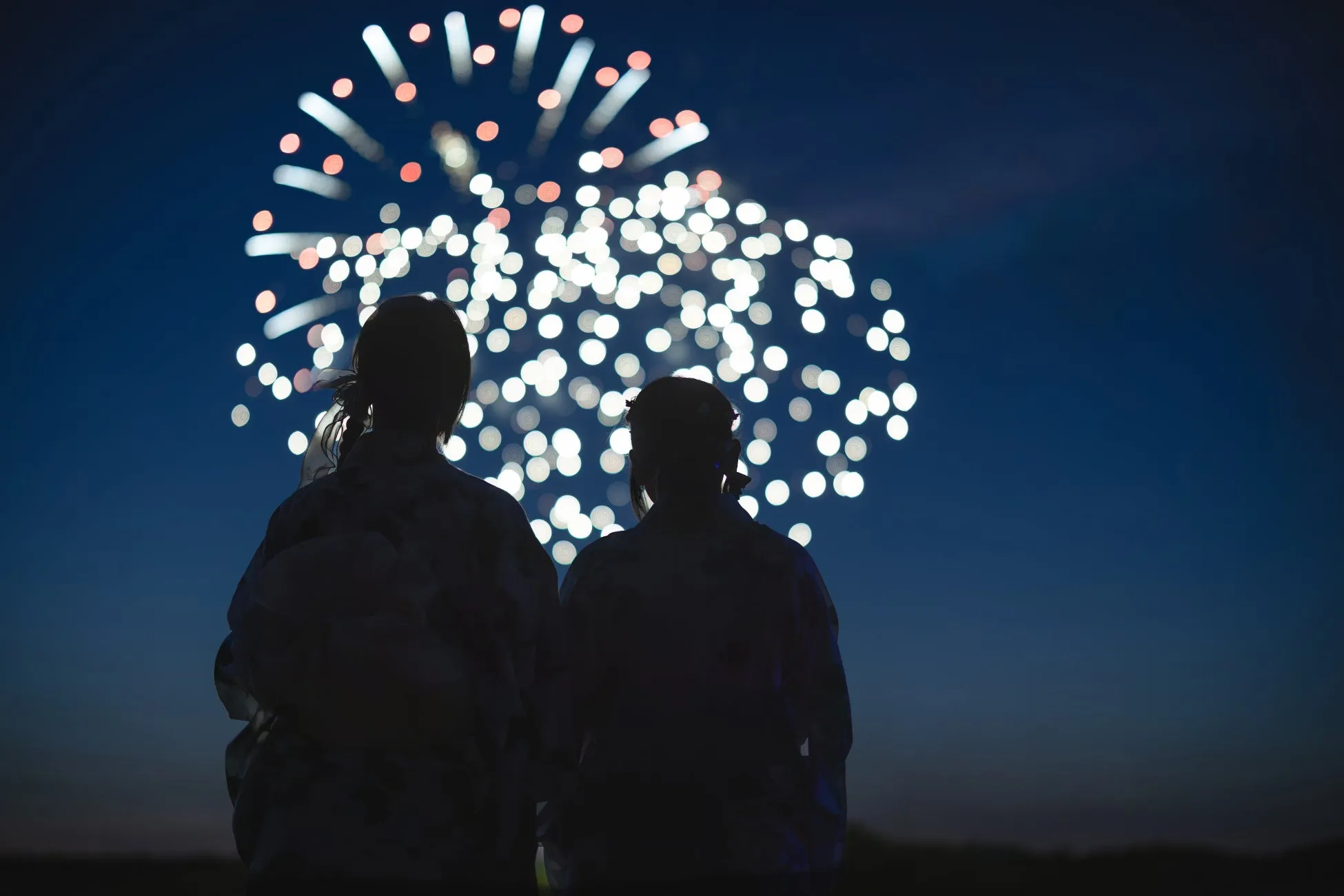 夜空に打ち上がる花火を見上げる二人