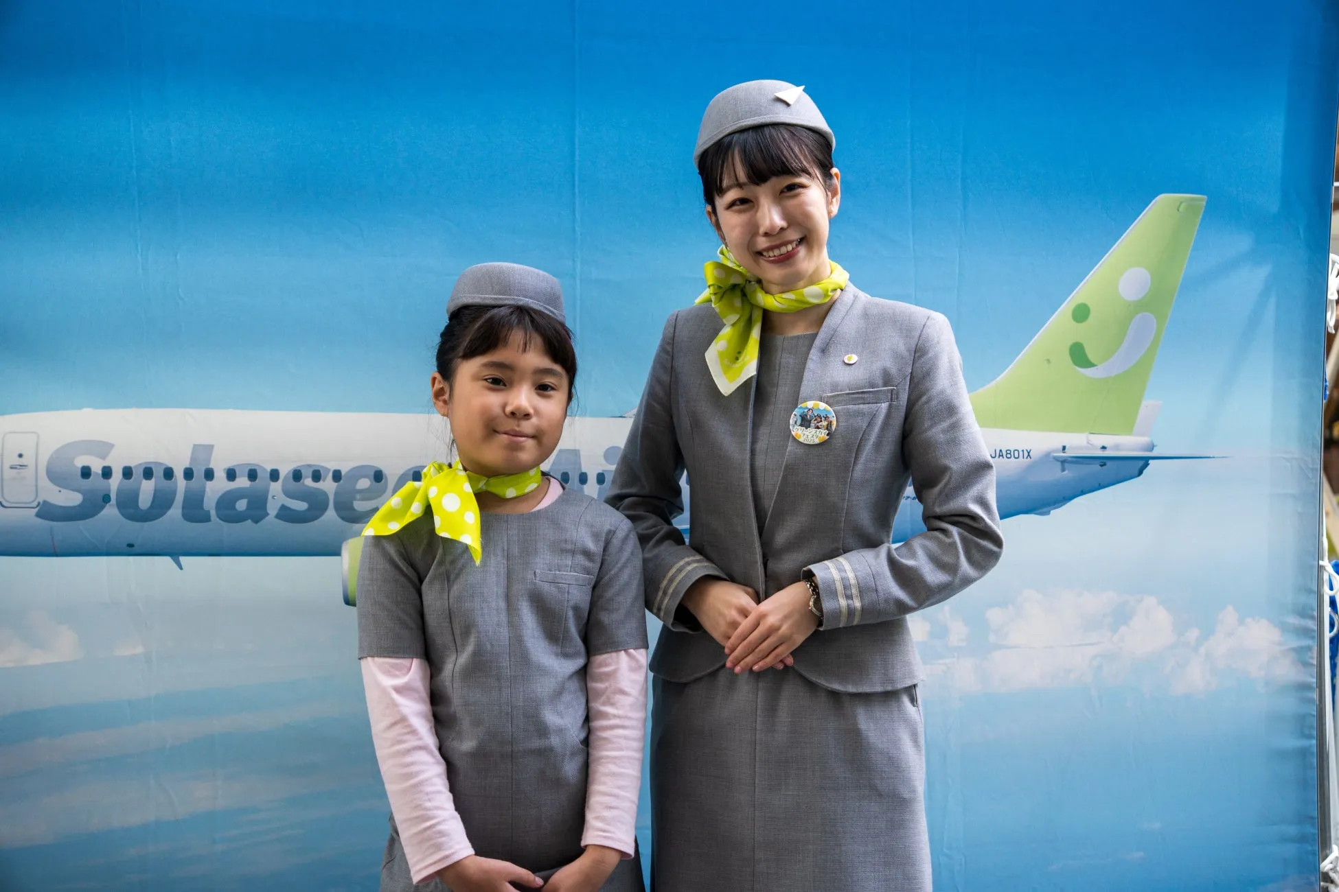 ソラシドエア制服の女性と女の子、背景に飛行機