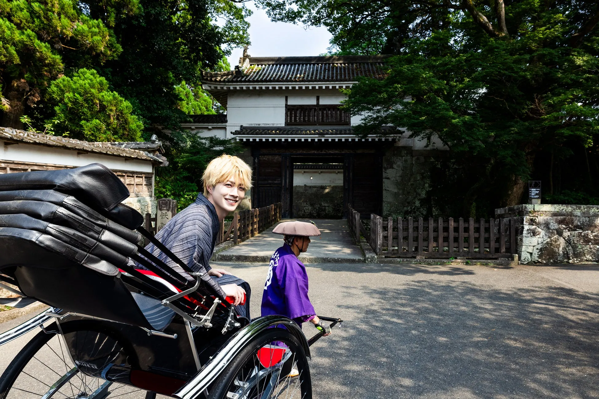 金髪の男性が人力車に乗って笑顔を見せる。