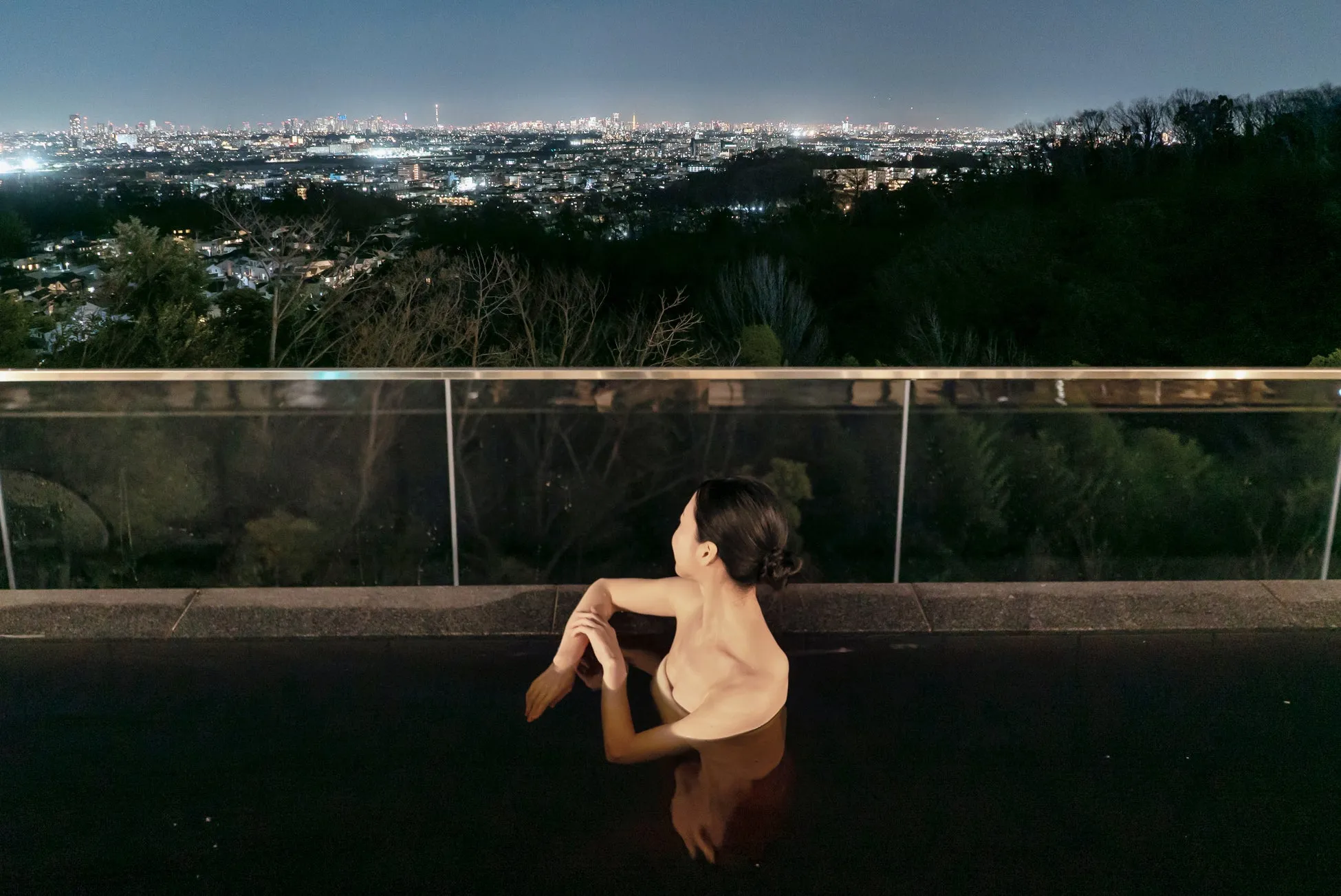 夜景を望む露天風呂でくつろぐ女性