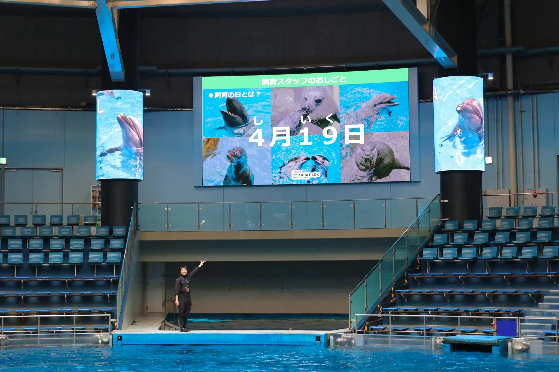 飼育の日を紹介するマクセルアクアパーク品川のスクリーンとスタッフ