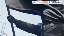 旗で顔覆われたスーツ姿の巨大な像 バンクシー新作がロンドン中心部に現る 「盲目的な愛国心への批判だ」との考察も