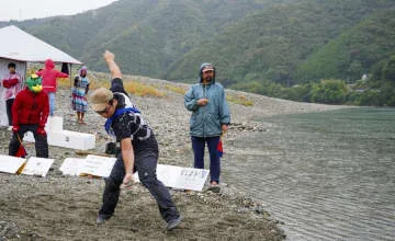 雨の中、水切りの腕前競う